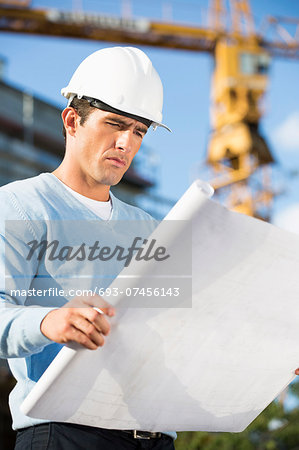 Male architect examining blueprint at construction site