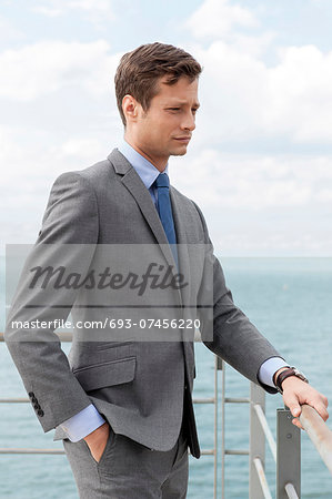 Thoughtful businessman with hand in pocket standing by terrace railings