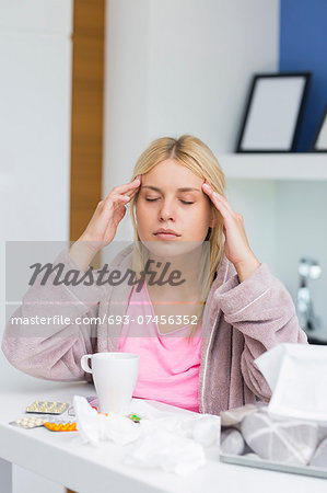 Young woman massaging head while suffering from cold