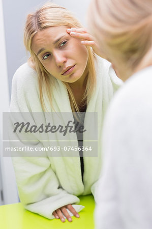 Young woman examining eye in mirror