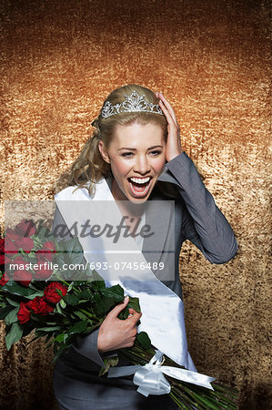 Woman screaming wearing Employee of the Month pageant paraphernalia against gold velvet background