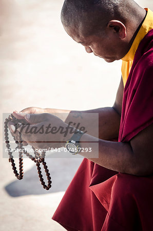 A Buddhist monk prays using a set of prayer beads (Japa Mala), Bodhnath stupa, Bodhnath, Nepal, Asia