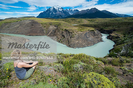 Woman sitting above a river bend in front of the Torres del Paine National Park, Patagonia, Chile, South America