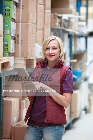 France, young woman using tablet computer in warehouse.