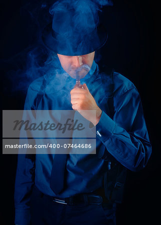 Man with gun holstered smoking a pipe on a black background