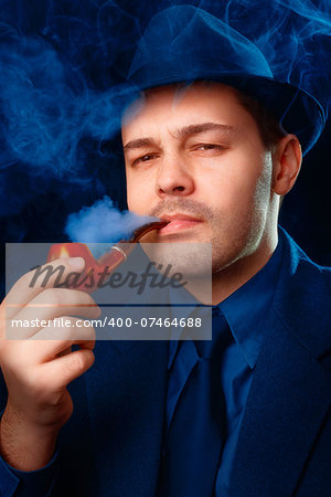 Man wearing a hat and suit smoking a pipe