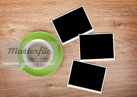 Cup of coffee and three photo frames on wooden table