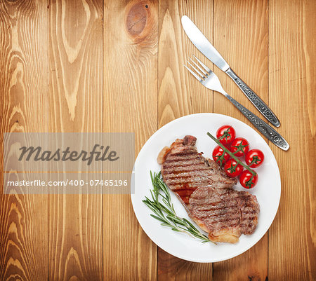 Sirloin steak with rosemary and cherry tomatoes on a plate. View from above with copy space