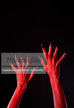 Red devil hands with black nails, Halloween theme, studio shot on black background