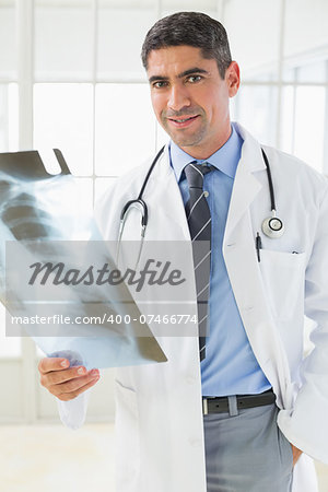 Portrait of a smiling male doctor holding a xray in the hospital