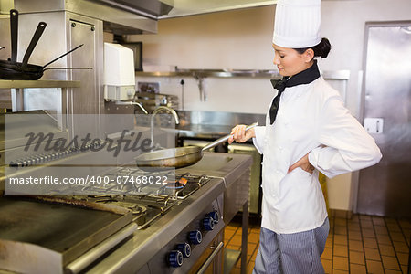 Side view of a female cook preparing food in the kitchen