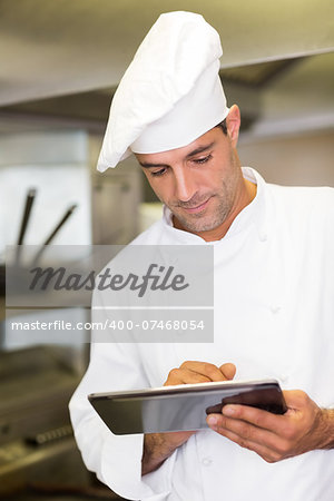 Concentrated male cook using digital tablet in the kitchen