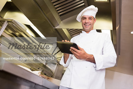 Portrait of a smiling male cook using digital tablet in the kitchen