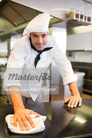 Portrait of a smiling male cook wiping the counter top in the kitchen