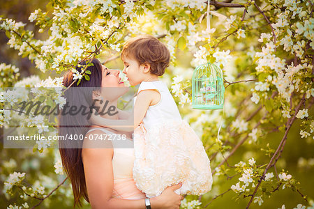 Happy woman and child in the blooming spring garden.Child kissing woman. Mothers day holiday concept