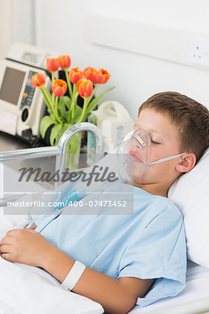 Sick little boy wearing oxygen mask in hospital bed