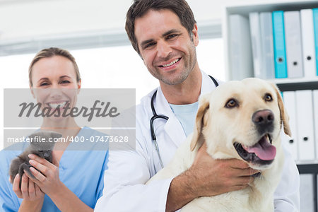 Portrait of confident veterinarians with dog and kitten in hospital