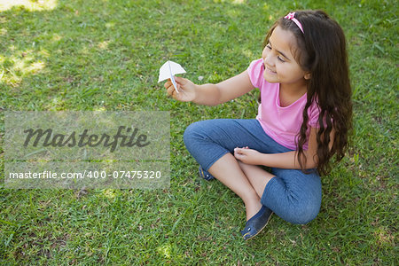 High angle view of a happy girl playing with a paper plane at the park