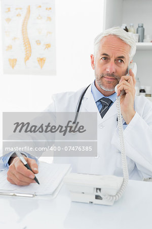 Concentrated male doctor writing reports while on call in the medical office