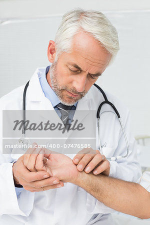 Male doctor taking a patients pulse at the medical office