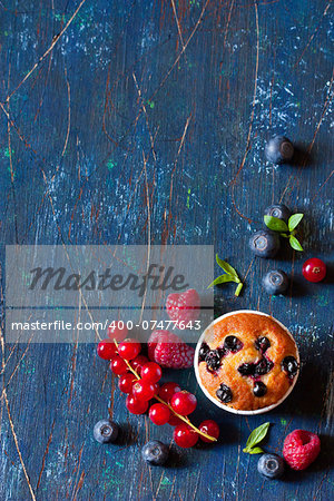 Sweet muffin surrounded by fresh berries with copy space for note or recipe.