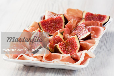 Prosciutto cured ham with ripe figs on white plate