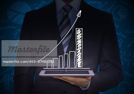 Man in suit holding tablet pc. Above the screen of the tablet are growing graph