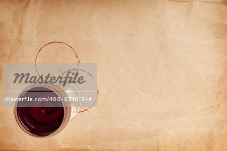 Red wine glass and stains on brown paper background with copy space