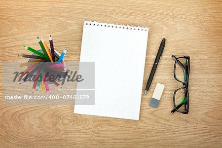 Blank notepad with office supplies and glasses on wooden table. Above view