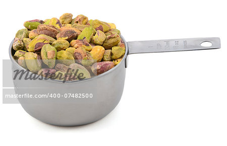 Shelled pistachio nuts presented in an American metal cup measure, isolated on a white background