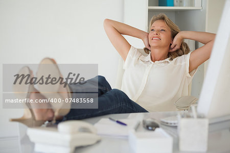 Casual businesswoman sitting at her desk with feet up in her office