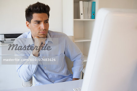 Casual businessman focusing at his desk in his office