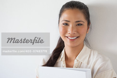 Casual businesswoman smiling at camera holding folder in the office