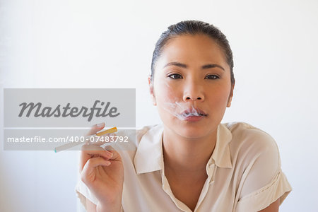 Casual businesswoman smoking an electronic cigarette in her office