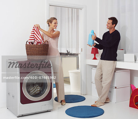 smiling woman with man dooing  laundry with washing machine