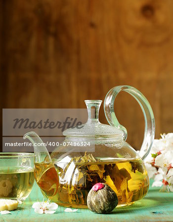 glass teapot with exotic green tea on a wooden table