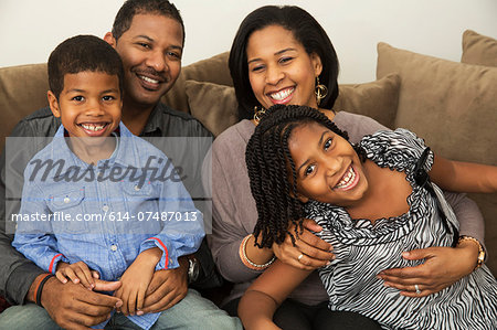 Portrait of mid adult parents with son and daughter on sofa