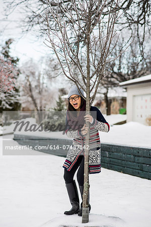 Young woman holding onto tree in slippy snow