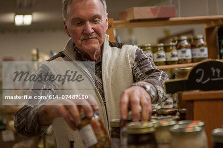 Shop keeper arranging jars in shop