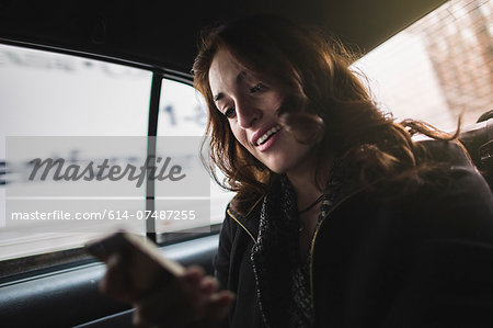 Young woman looking at cellphone in taxi
