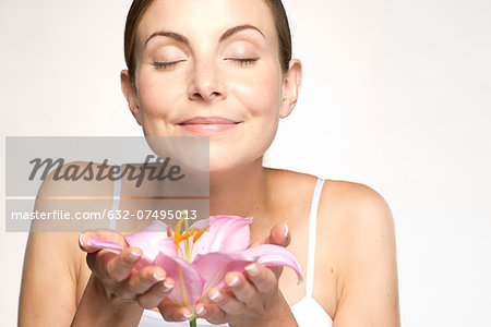 Young woman holding lily in cupped hands, eyes closed Young woman holding lily in cupped hands, eyes closed