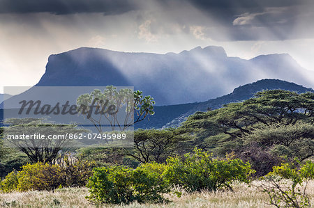 Kenya, Shaba National Reserve, Isiolo County. Rays of sunlight break through a threatening sky near Ol doinyo Sabachi, a prominent flat-topped massive sometimes called Lololokwi.