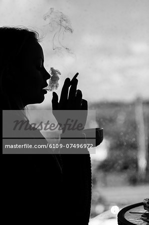 Silhouette of an attractive woman smoking cigarette in black and white