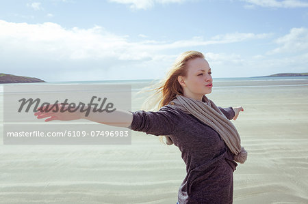 Attractive woman opening her arms in front of the ocean on the beach