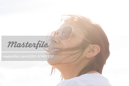 Woman in sunglasses looking up at sky enjoying the sunlight