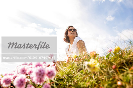 Woman sitting in field of wild flowers reflecting on life