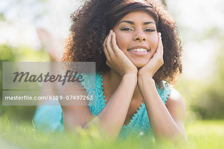 Gorgeous cheerful brunette lying on grass looking at camera in nature