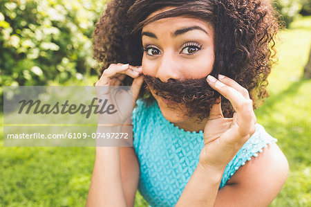 Gorgeous content brunette pretending having mustache in nature