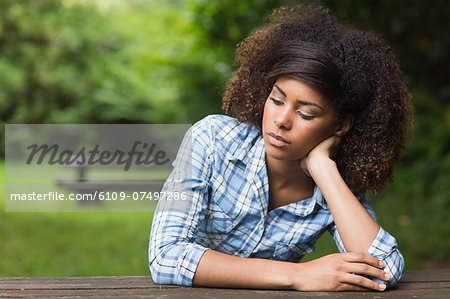 Gorgeous day dreaming brunette sitting at picnic table in nature