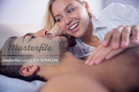 Pretty blonde woman lying next to her boyfriend looking at him